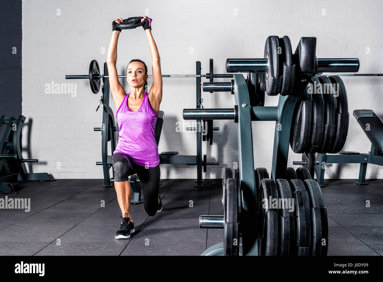 Athletic young woman doing exercise with barbell plate in gym Stock ...