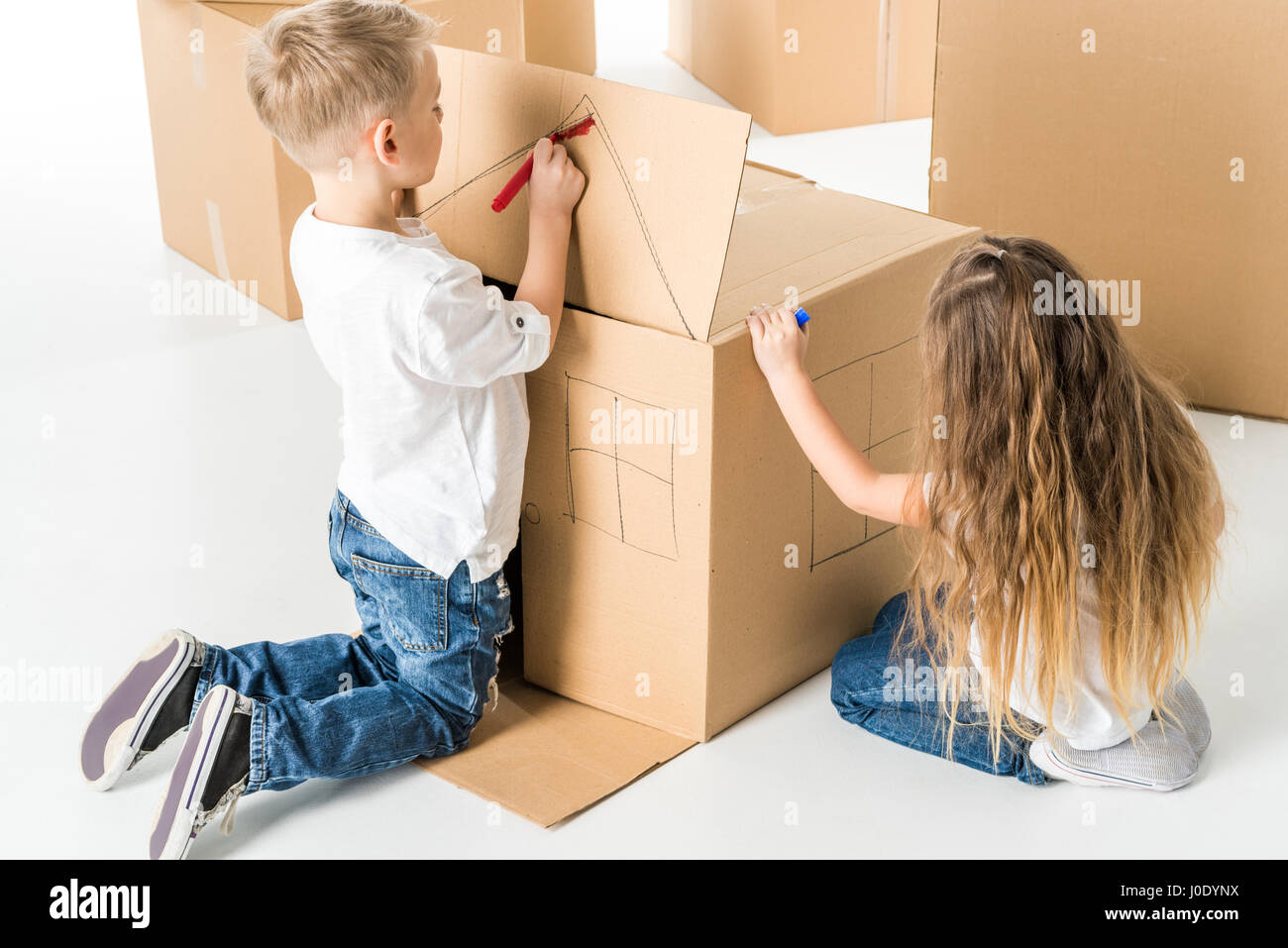 Cute little boy and girl drawing house on cardboard box Stock Photo