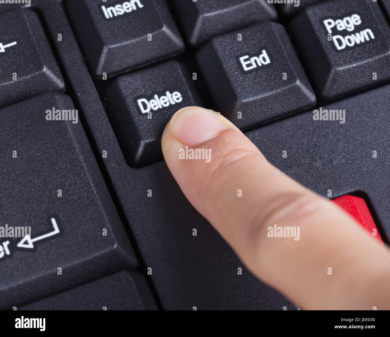 finger pushing delete button on a keyboard of computer Stock Photo