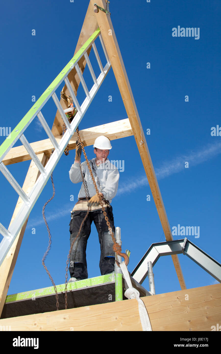 construction worker at work with winch on roof construction Stock Photo