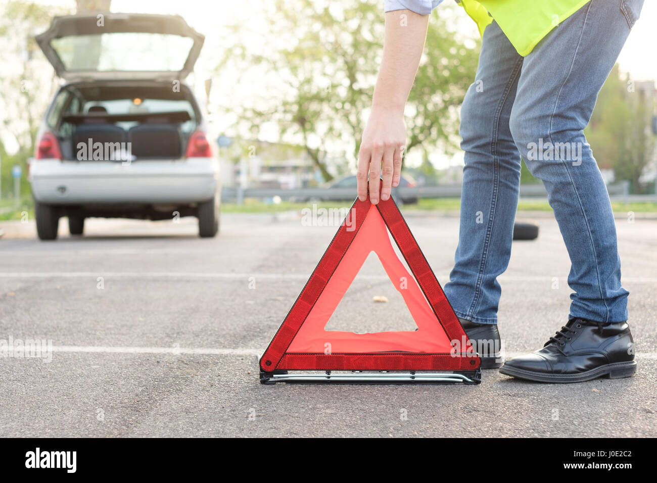 Man placing a reflective red triangle after car breakdown Stock Photo ...