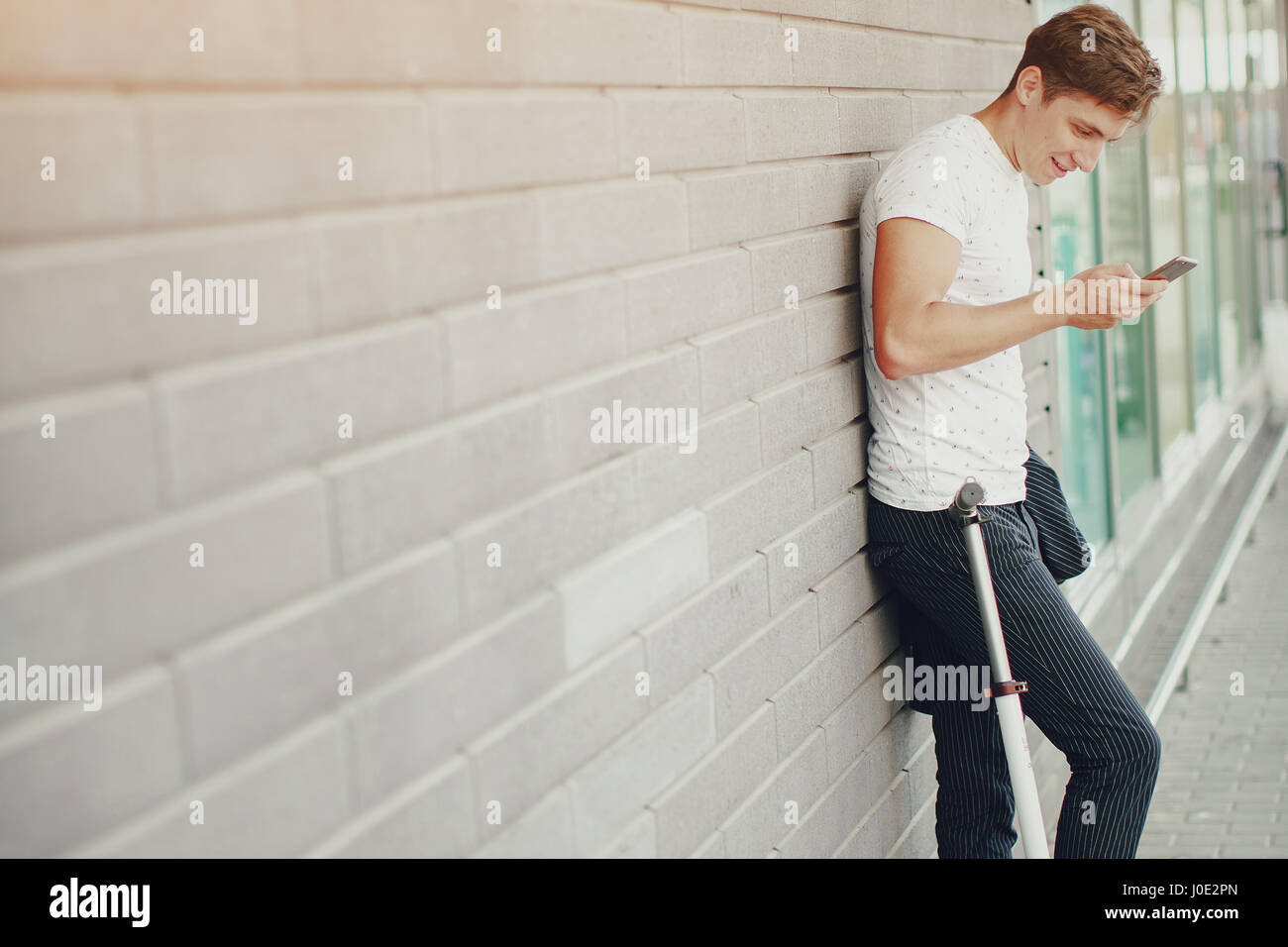 young man on the scooter walks through the city on Sunny