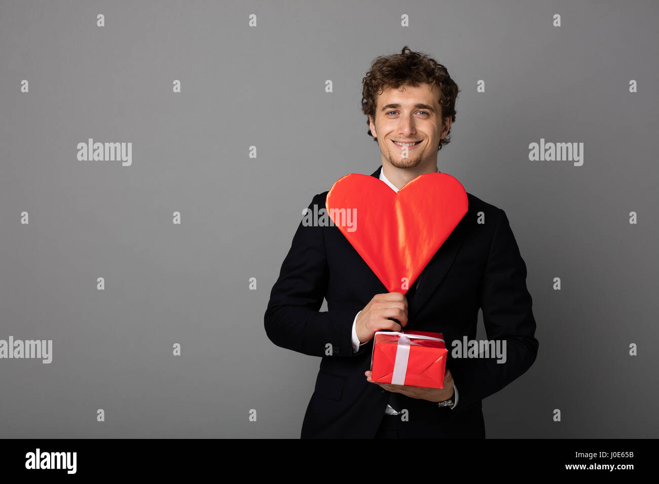 handsome elegant man in black elegant suit holding a heart and a red ...