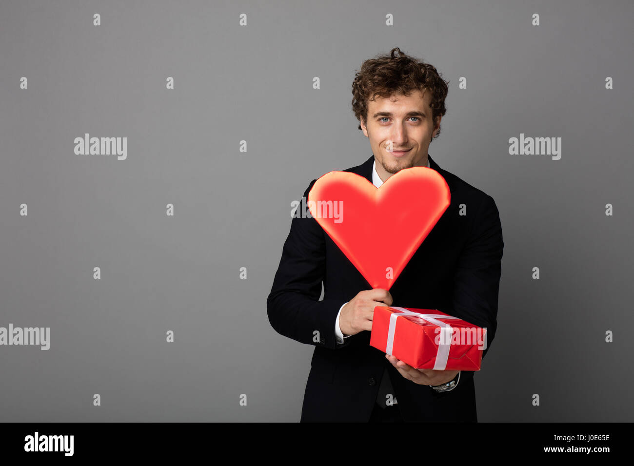 handsome elegant man in black elegant suit holding a heart and a red ...
