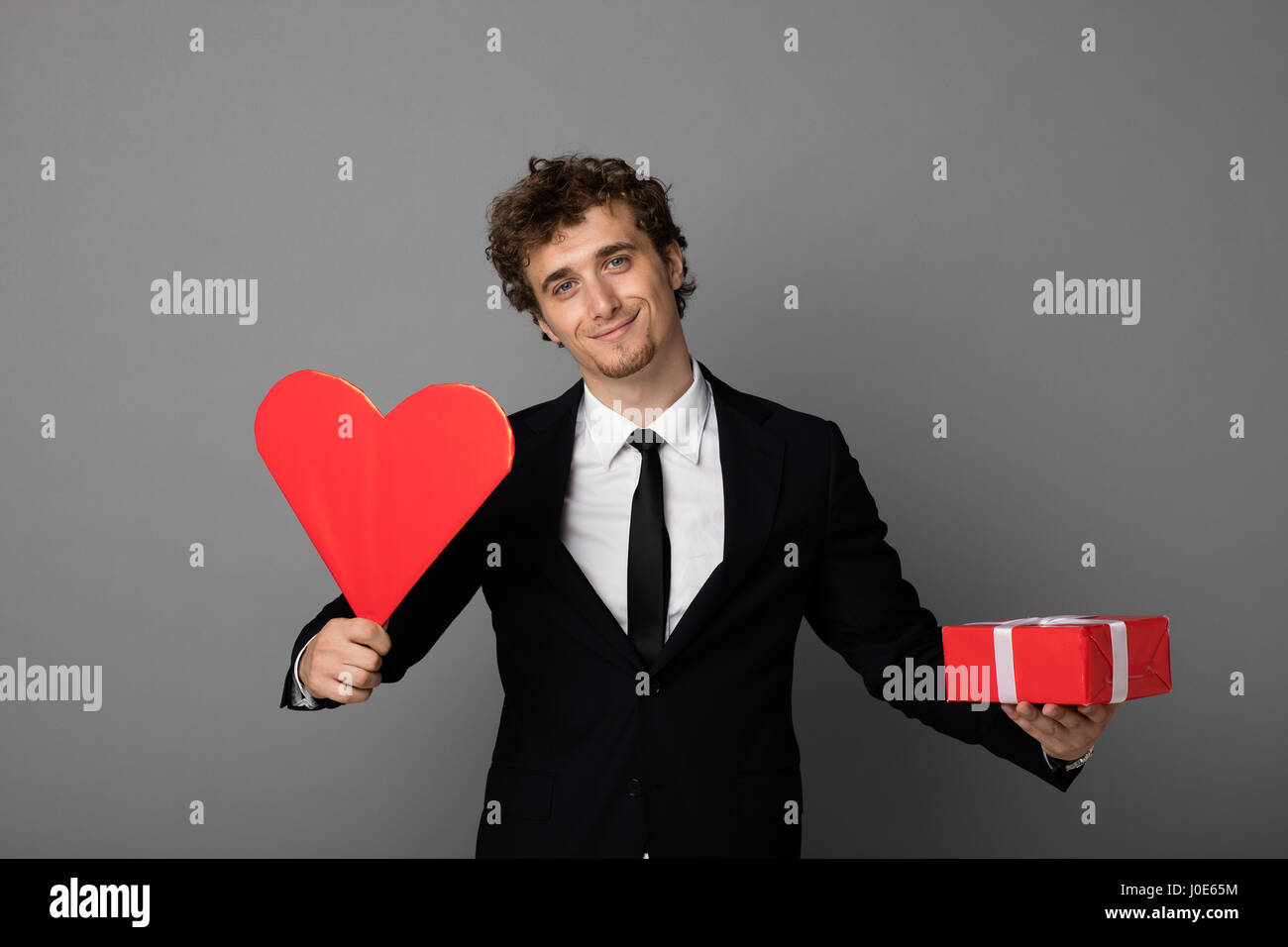 handsome elegant man in black elegant suit holding a heart and a red ...
