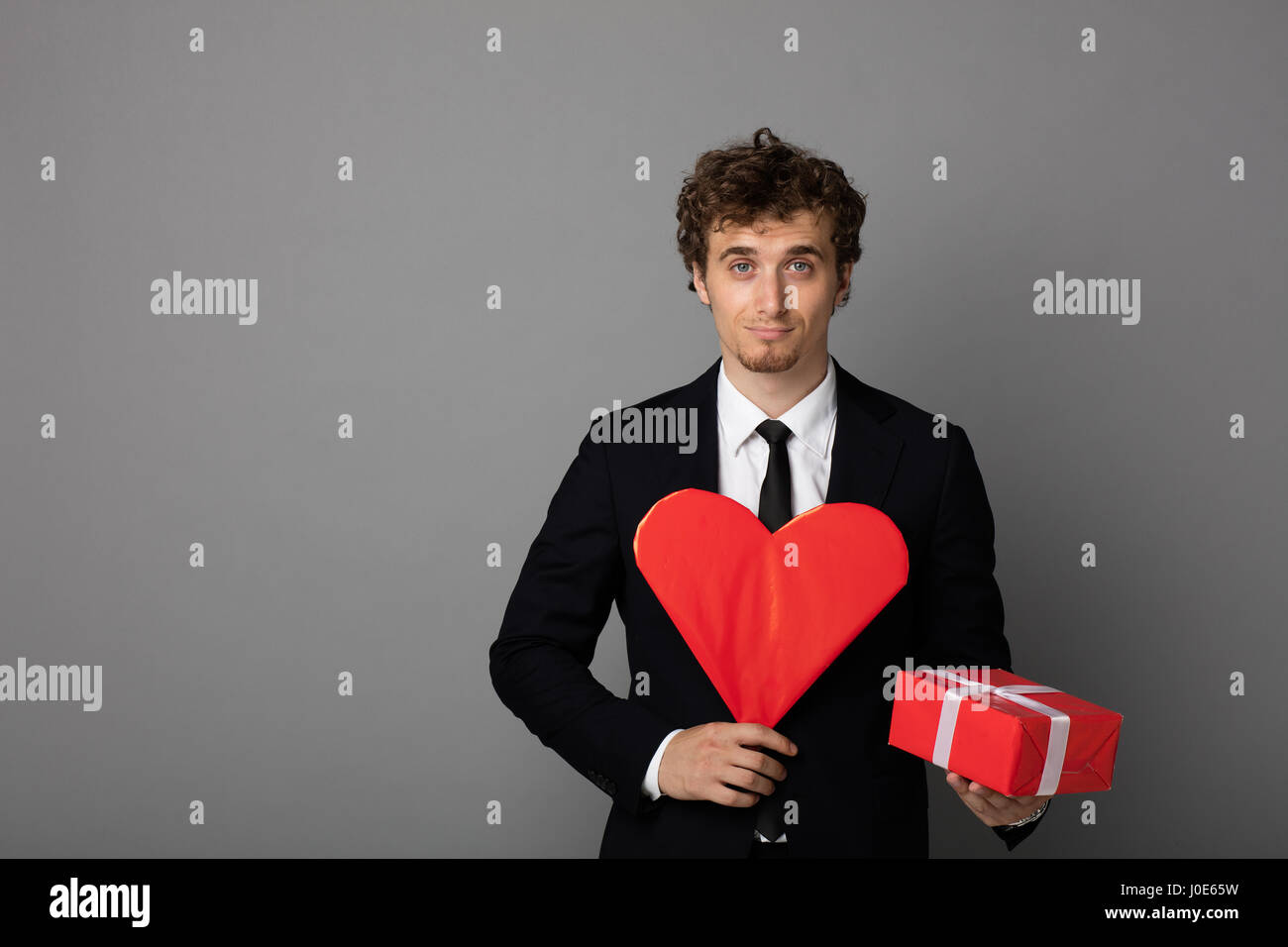 handsome elegant man in black elegant suit holding a heart and a red ...