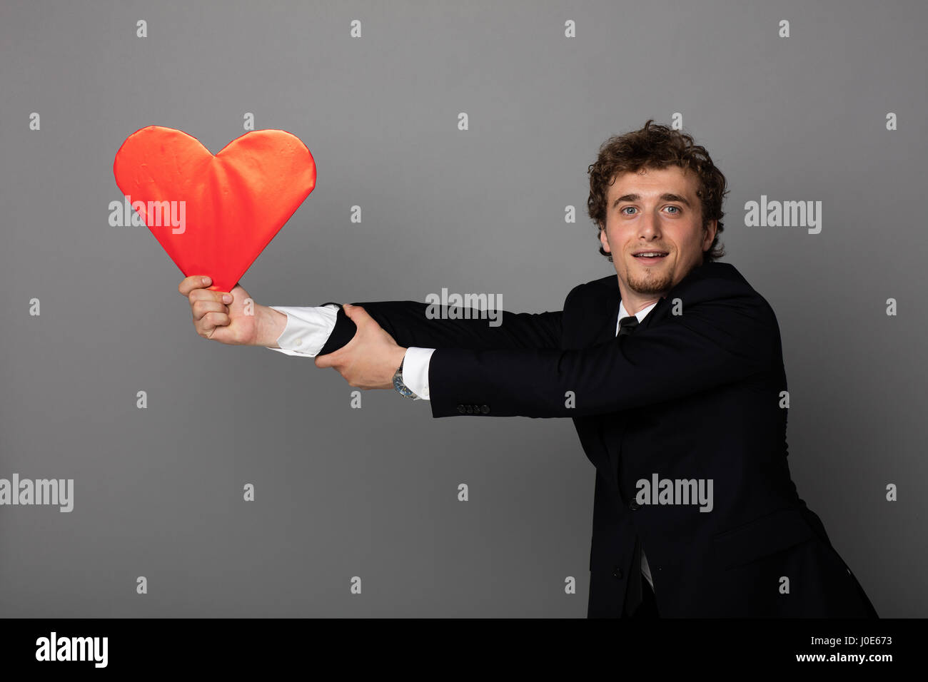 handsome young elegant men in black suit trying to hold his flying red ...