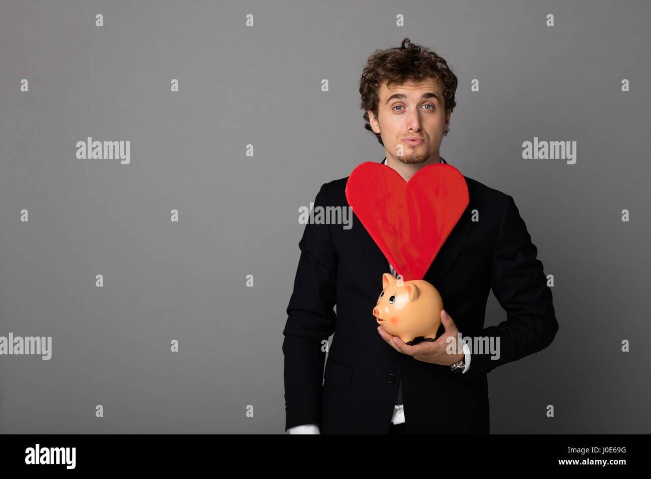 handsome young man in black suit having in hands a red heart and a ...