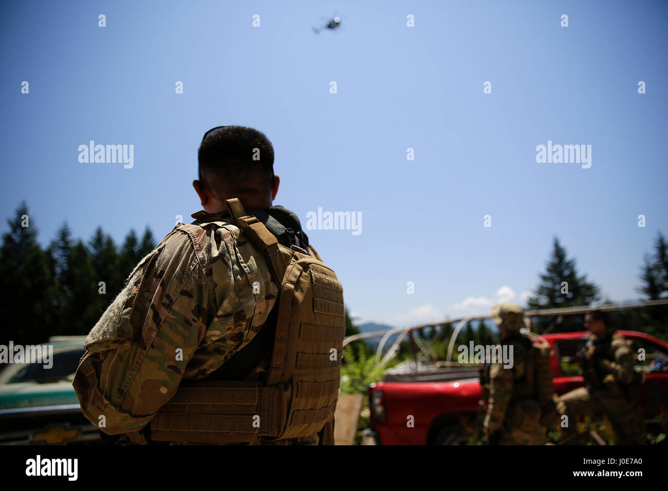 A helicopter flies over law enforcement officers during an anti-marijuana raid on July 15, 2015. Yurok Indian Reservation, California, United States. Stock Photo