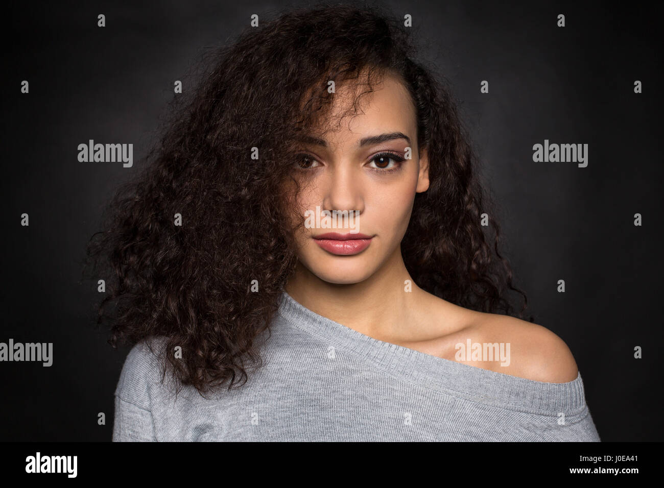 Young woman with curly hair in gray sweater, portrait, fashion, lifestyle Stock Photo