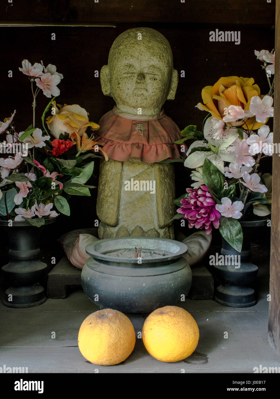 Jizo statue with flowers and fruit mikan,manderin offerings, buddhist