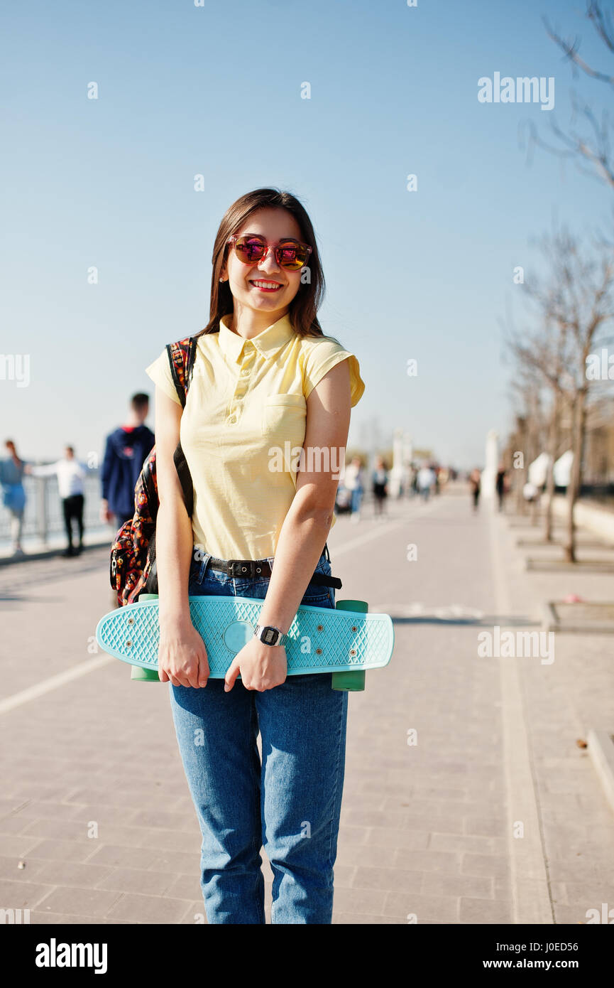 Young teenage girl with small skateboard, board, wear on yellow t-shirt, jeans and sunglasses Stock Photo - Alamy