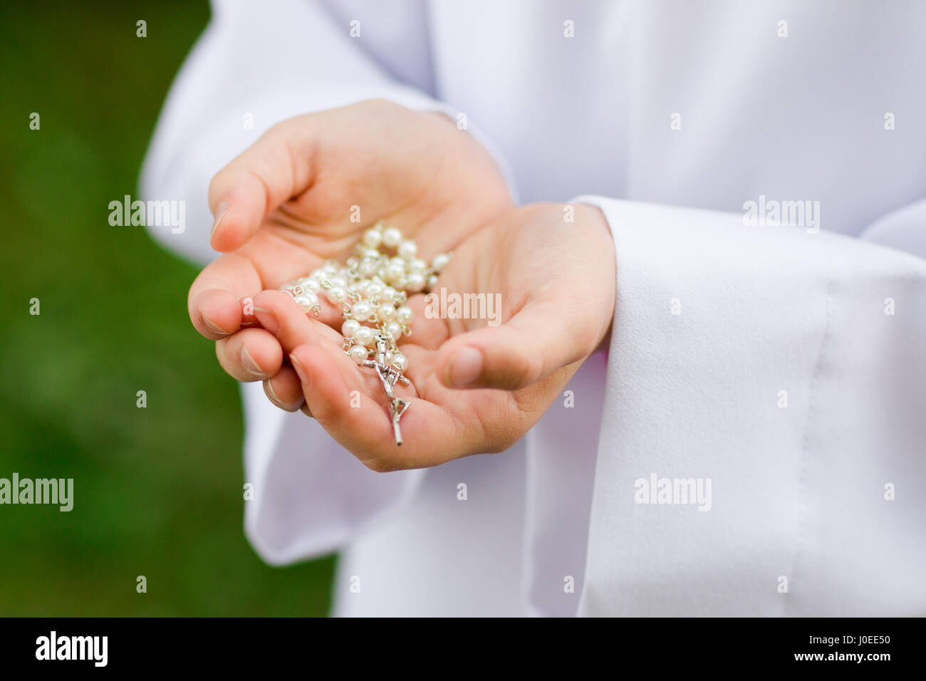 First Holy Communion concept - close up on rosary on child's hands Stock Photo