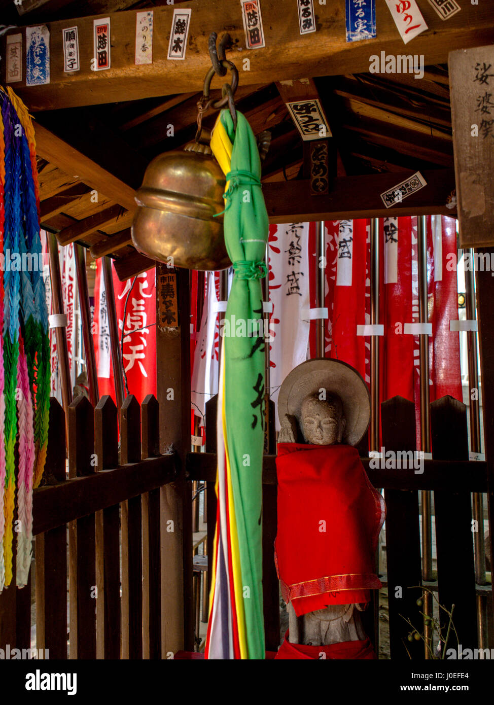 Jizo statue with red bib. Belland bell pull to sound when making prayers. Toyokawa Inari Betsuin