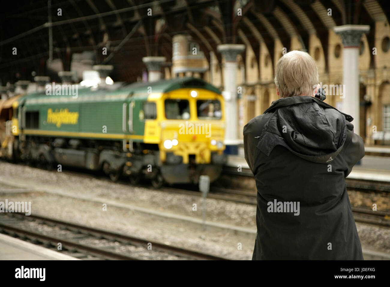 Rail enthusiast photographing a Freightliner Class 66 diesel loco at York station, UK Stock Photo