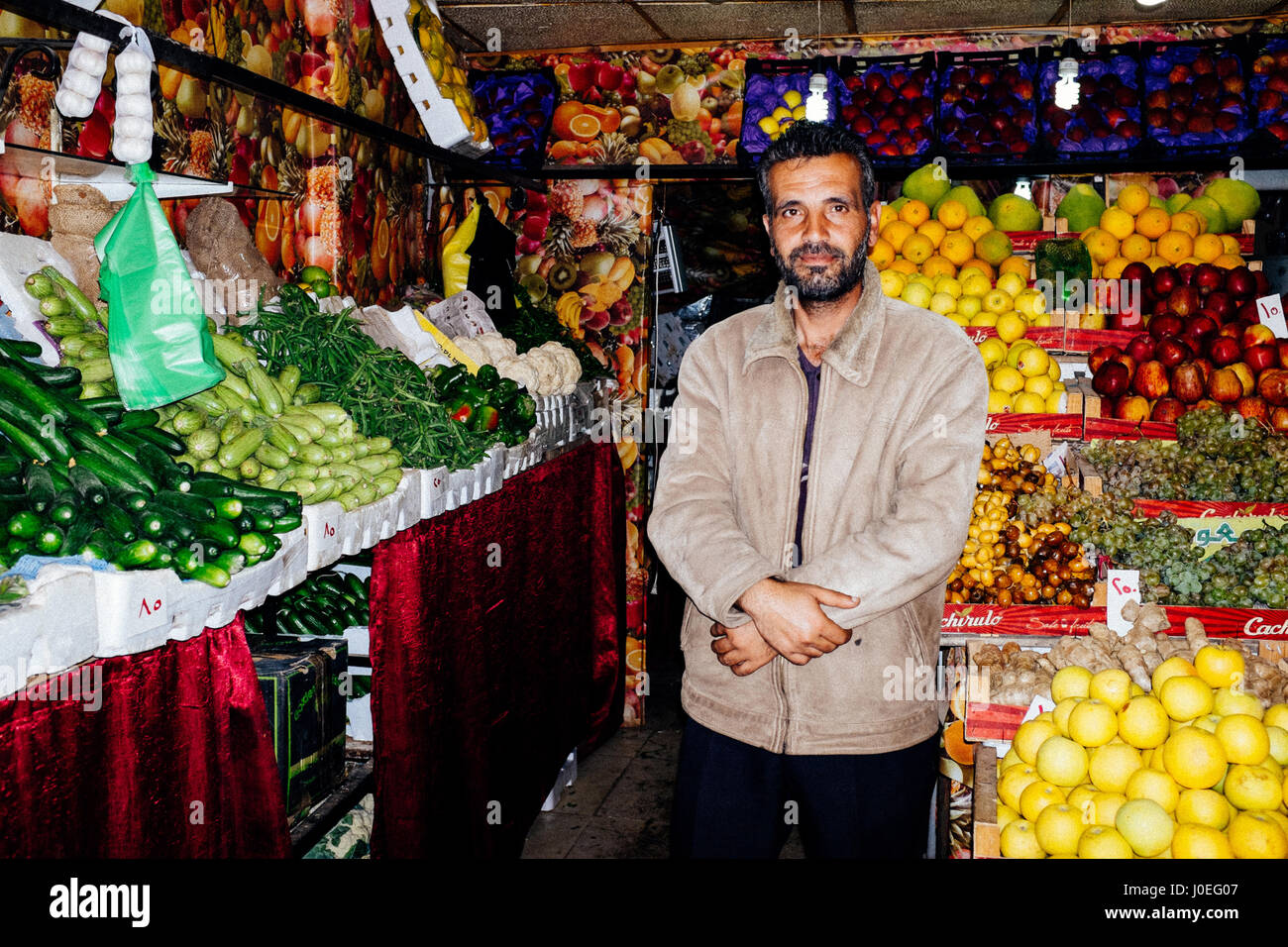 A friendly man is selling fresh vegetables and fruits at the local market in Amman, Jordan. Stock Photo