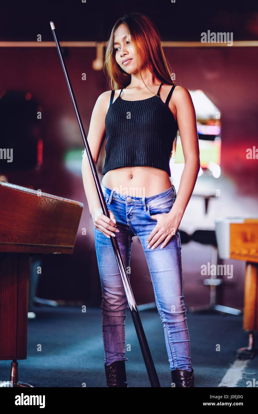 Young beautiful girl in a billiard club, with cue stick posing Stock Photo