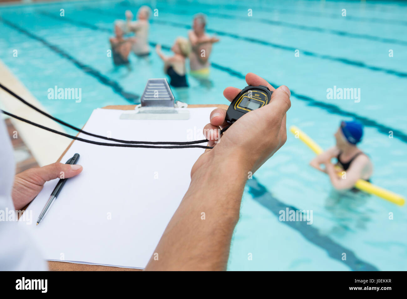 handsome swim trainer with stopwatch at competition swimming pool
