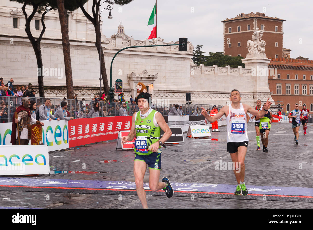 Rome, Italy - April 2nd, 2017: Athletes participating in the 23rd marathon in Rome arrive exhausted at the finish line on Via dei Fori Imperiali. Stock Photo