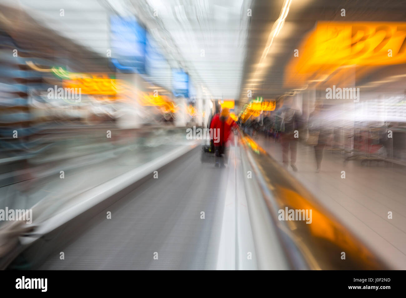 Rushing through the airport terminal to catch the next layover flight. Motion blurry image on an escalator. Last minute hurry to not to be late to the Stock Photo