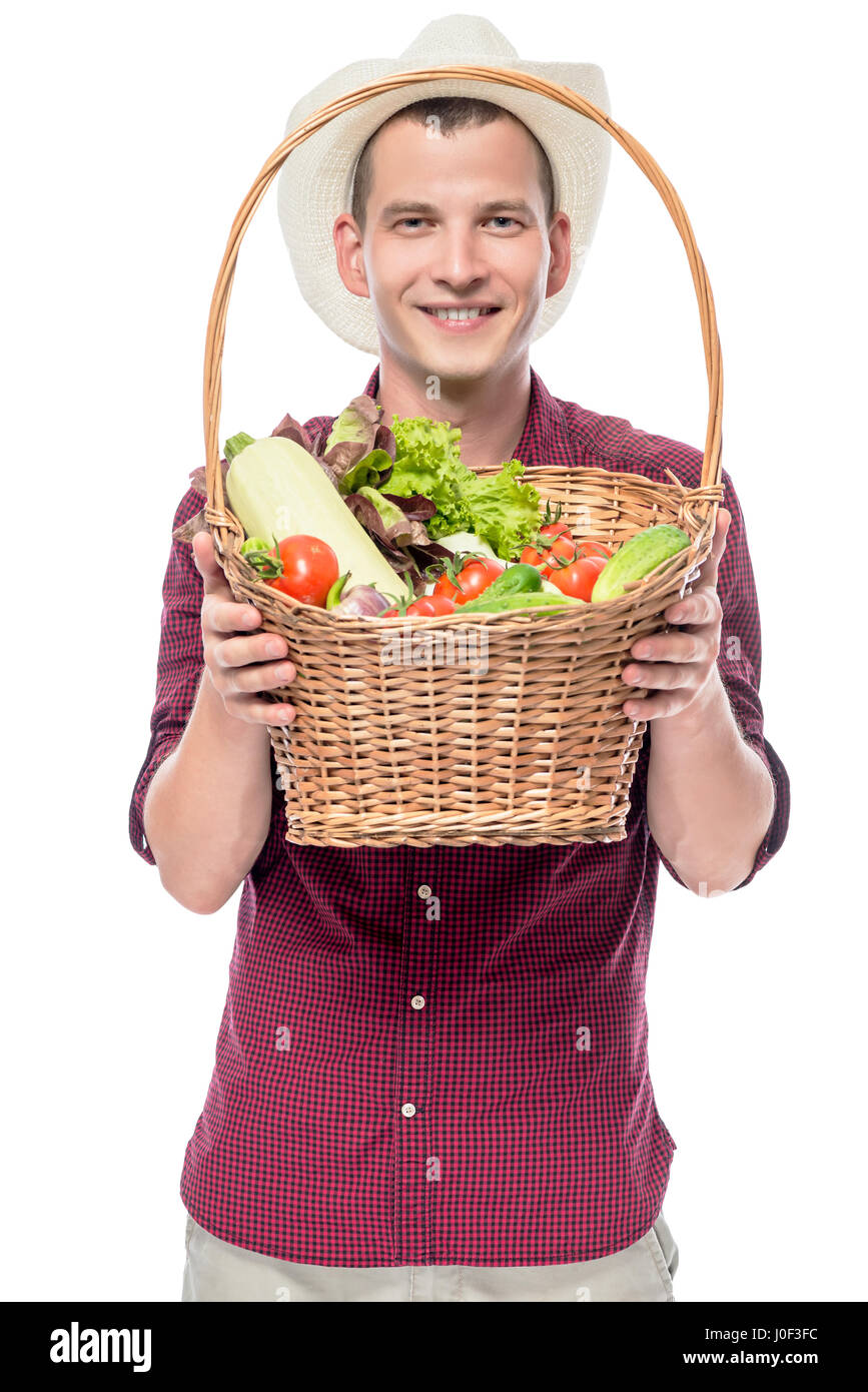 Smiling man shows a basket with grown vegetables in his garden isolated ...