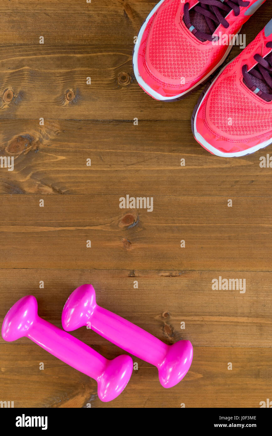 pink sneakers and a dumbbell in the corners of the frame on the wooden ...