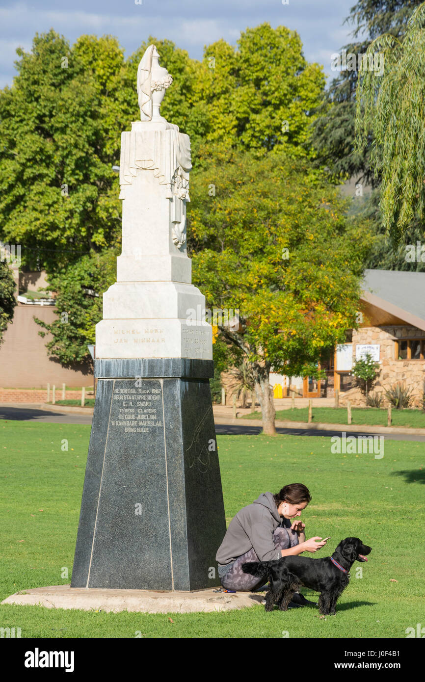 Young woman and dog by Naauwpoort Monument on The Main Square Green, Clarens, Free State Province, South Africa Stock Photo