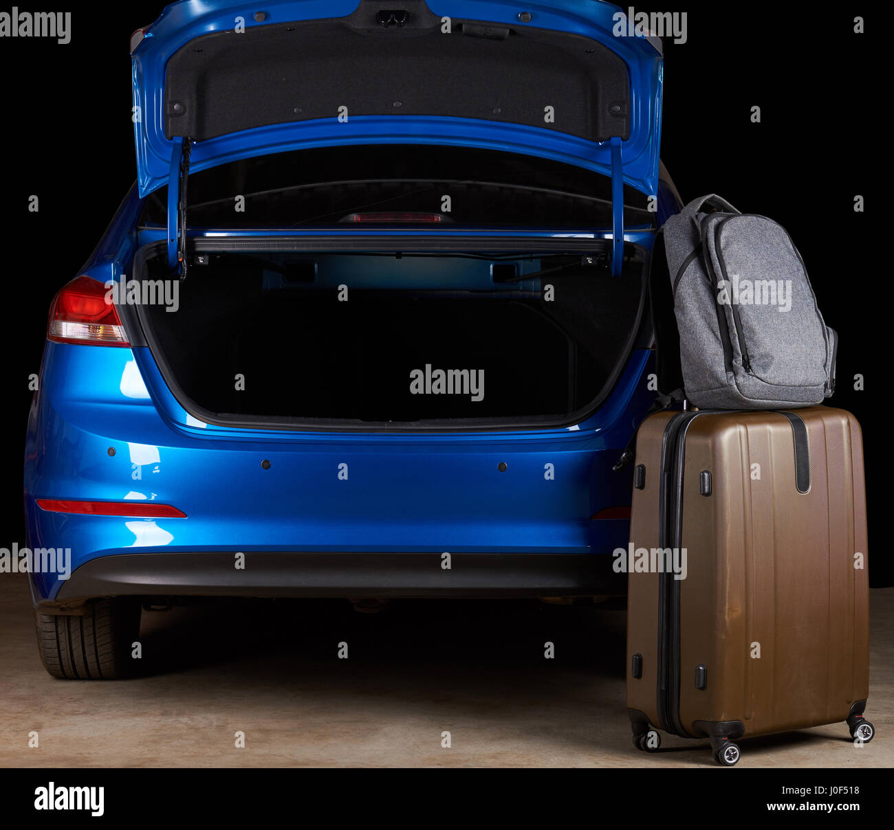 Luggage bags stand next to open car empty trunk isolated on black background Stock Photo