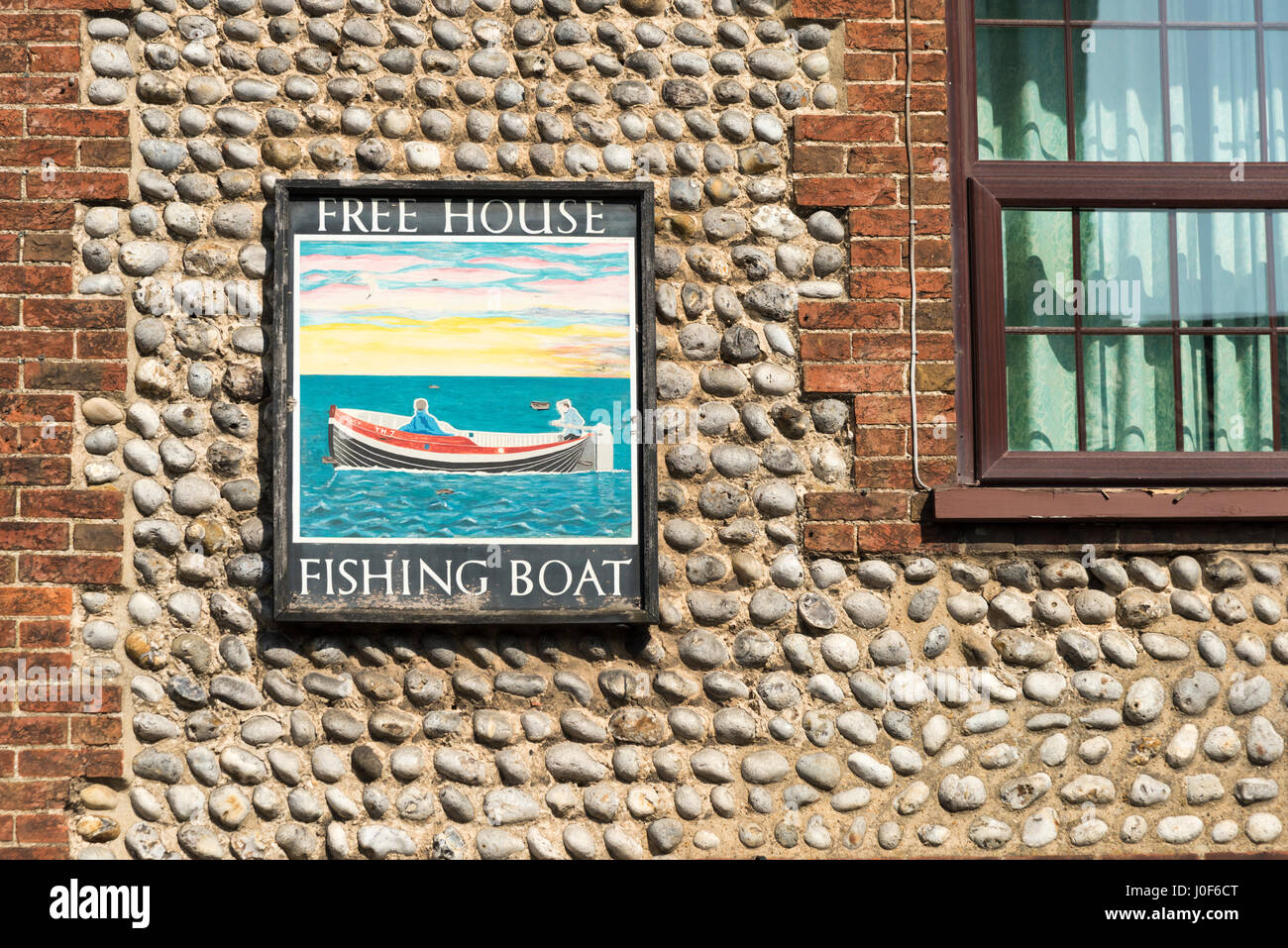 A pub sign on a traditional Norfolk flint wall for the Fishing Boat pub