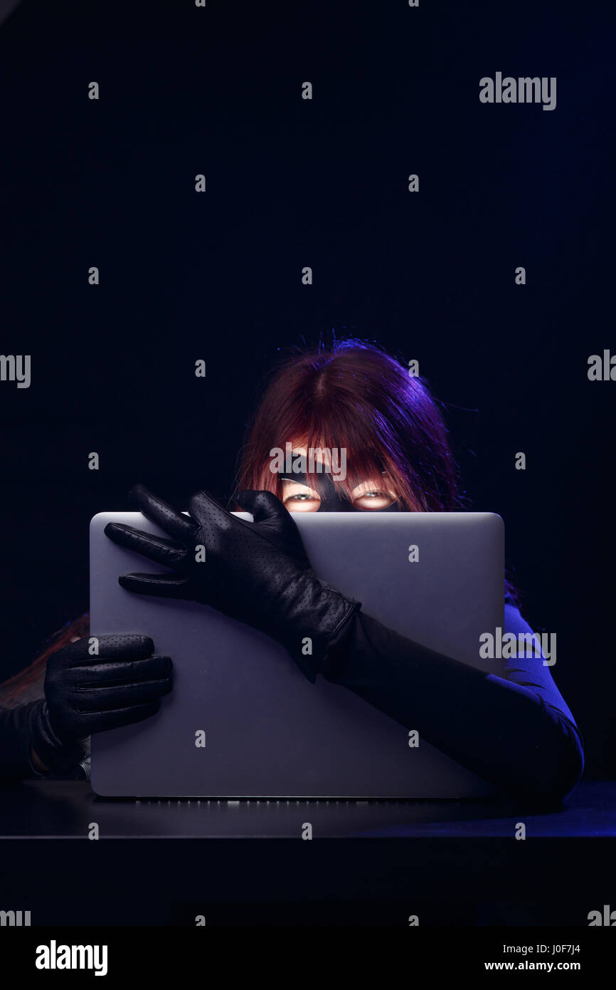 Thief in mask holds laptop in hands at night Stock Photo - Alamy