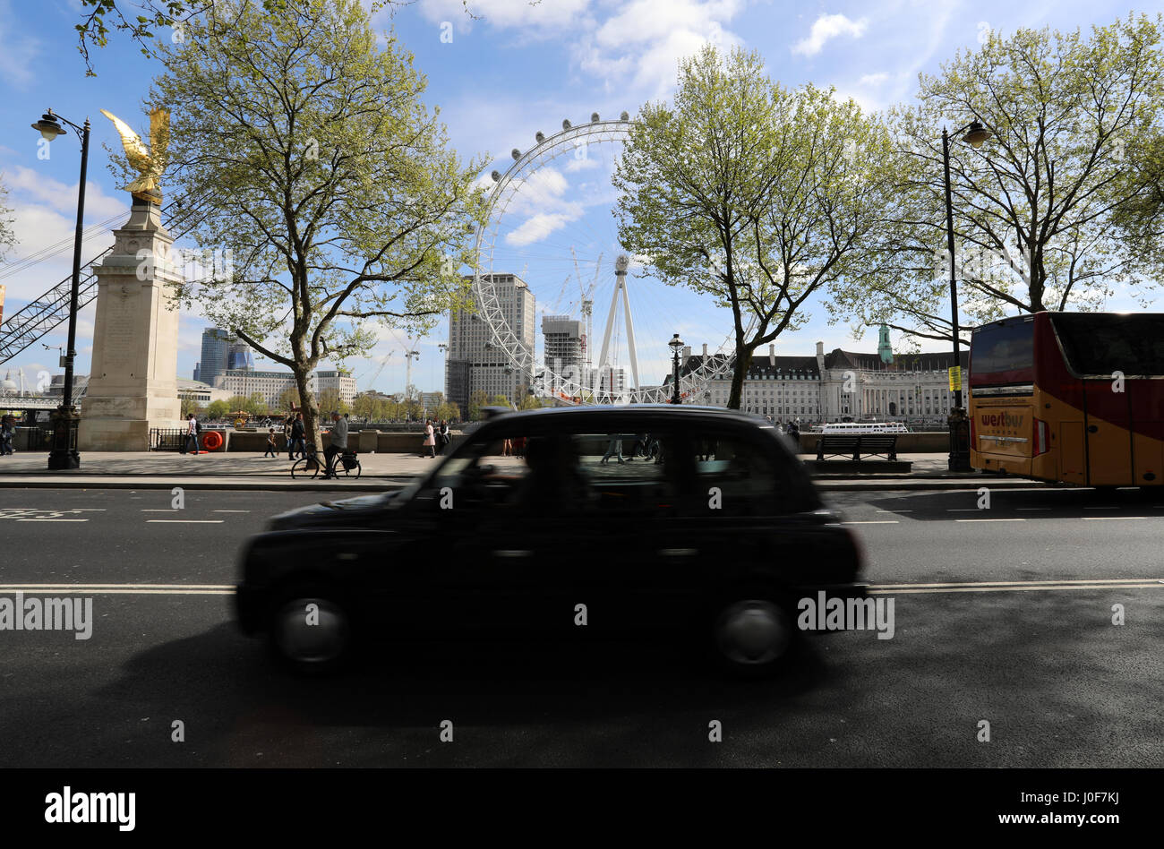 A black London taxi drives along Victoria Embankment in central London, with the London Eye in the background Stock Photo