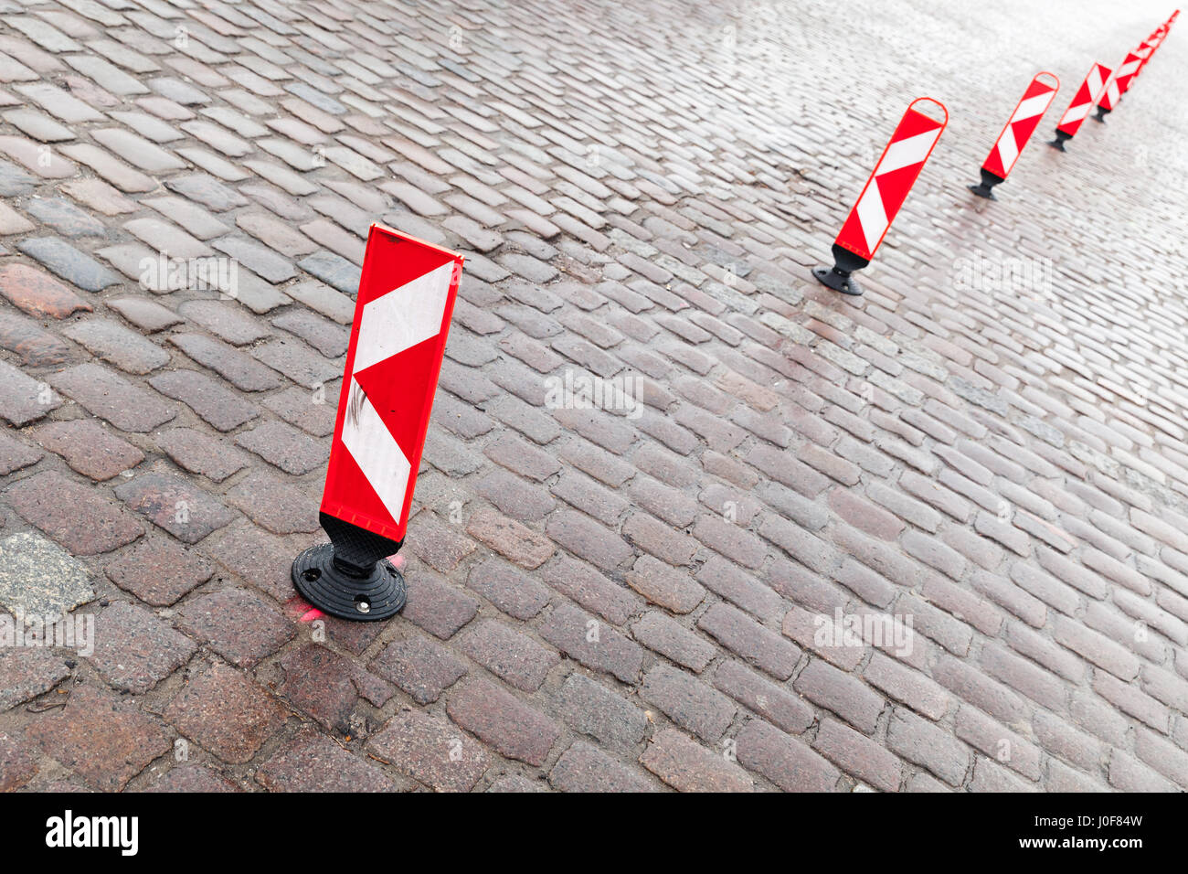 vertical red and white striped caution road signs stand in a row to