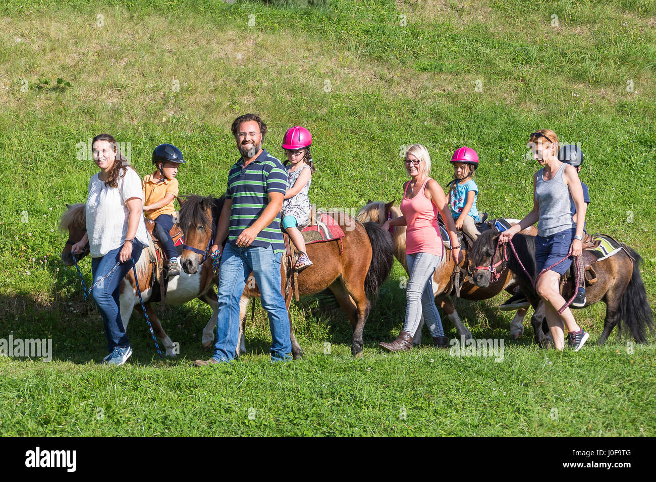 Shetland Pony. Adults leading ponies with kids on horseback. Austria