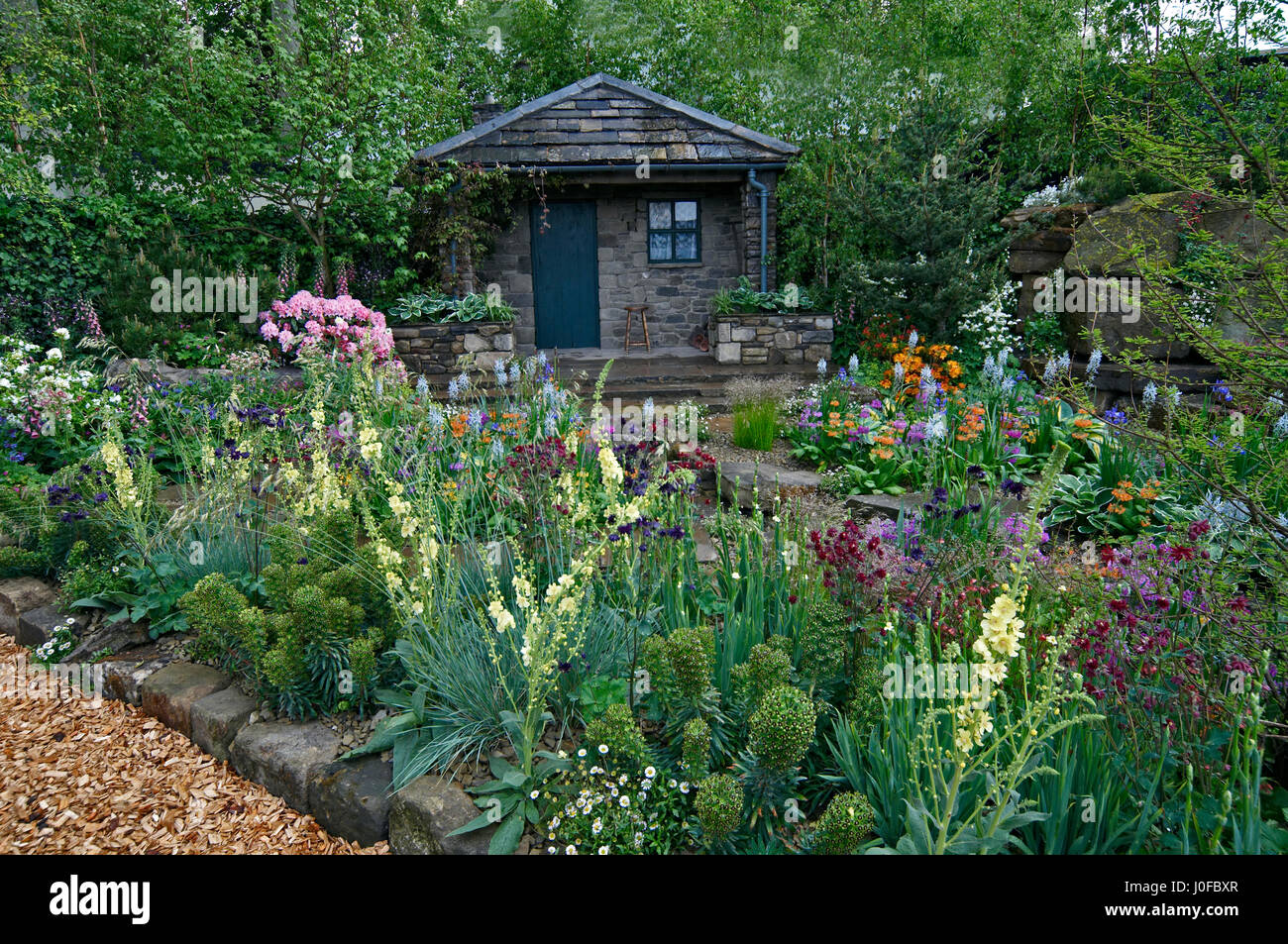 A country cottage and garden situated in a wooded rockery with a colourful display of flowers Stock Photo