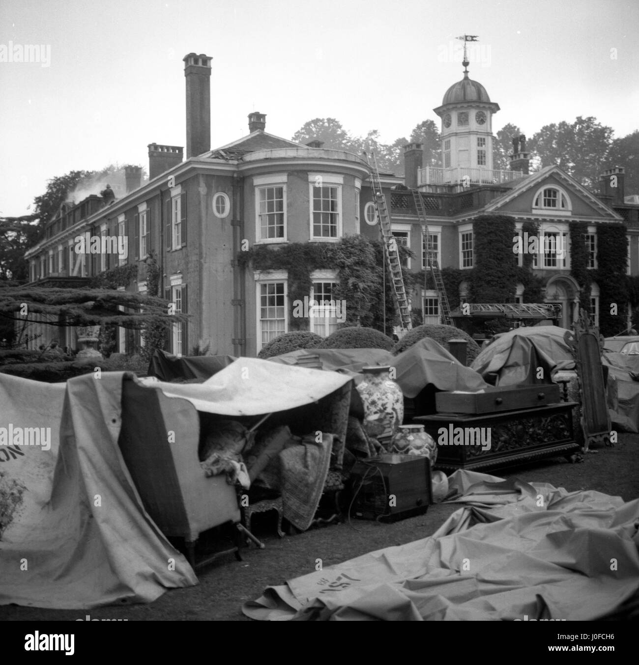 Valuables and furnishings from inside the building gathered outside on the lawn in front of Polesden Lacey, near Dorking, Surrey, after a fire broke out in the roof. Stock Photo
