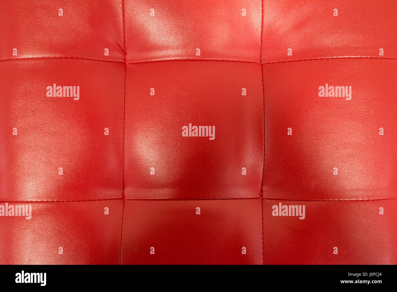 Close-up of vintage red leather couch with seams and buttons. Stock Photo