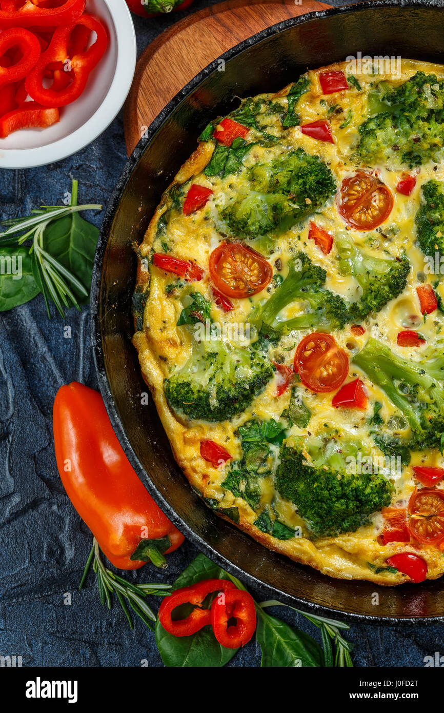 Frittata with broccoli, spinach, sweet peppers and tomatoes in iron