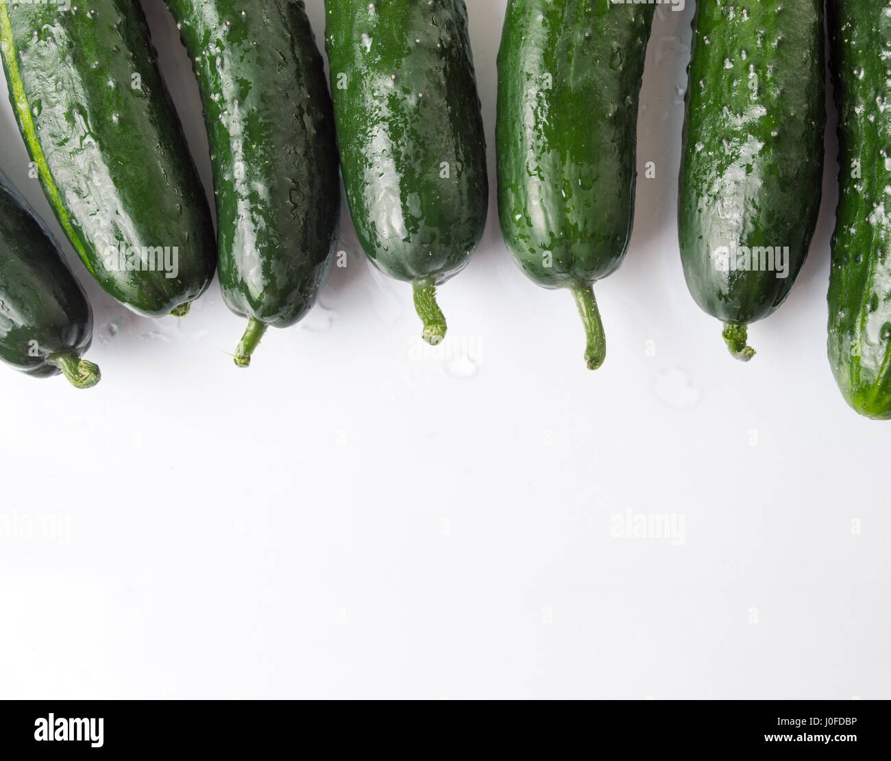 Wet cucumbers on a white wooden table Stock Photo