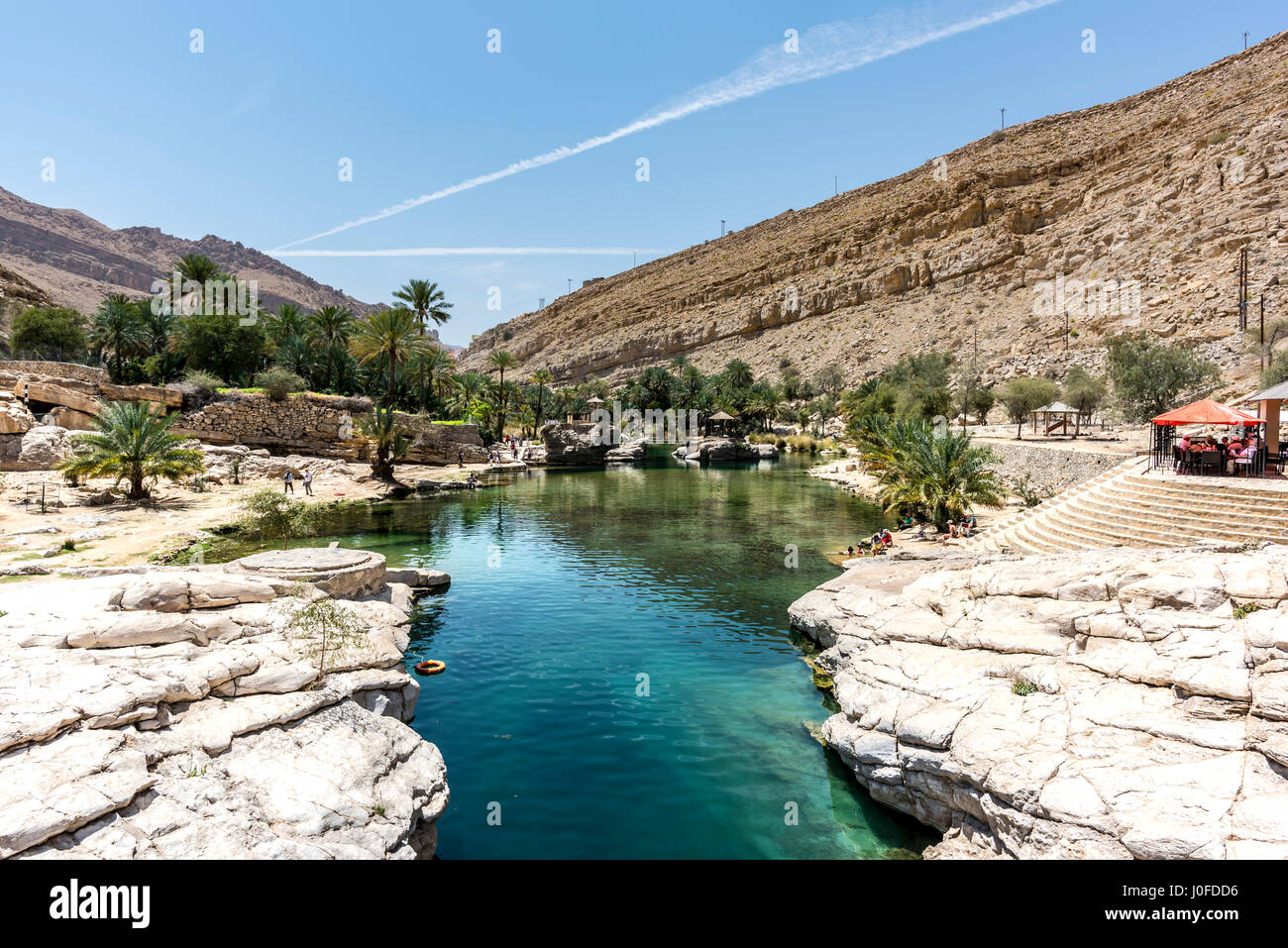 Tourists close to the river (with turquoise water) and pool of Wadi Bani Khalid, Oman Stock Photo