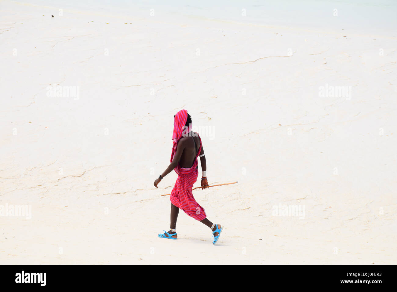 Masai walking down nungwi beach Zanzibar Stock Photo