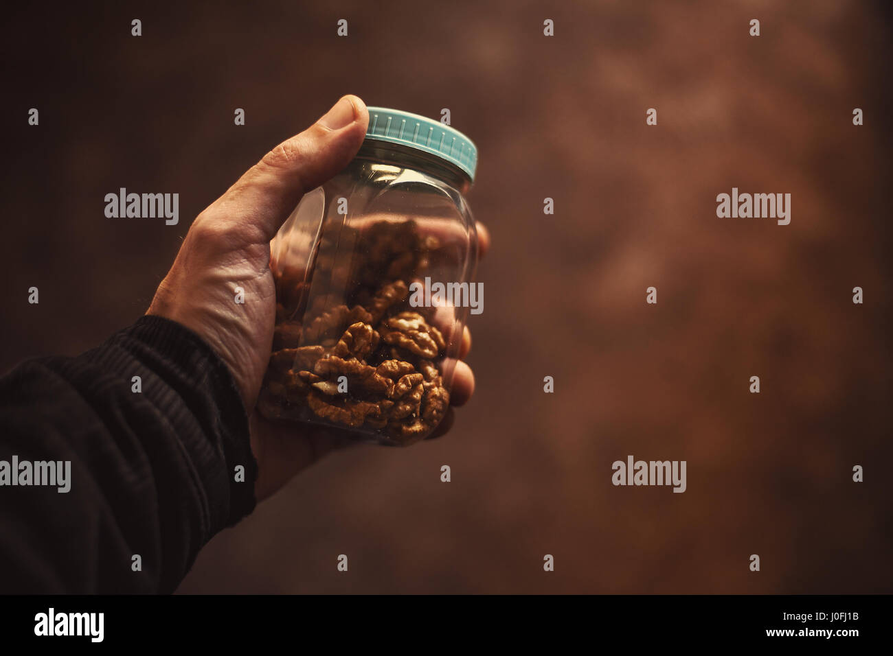 Closeup view on jar with walnuts, hand held by a man. Stock Photo