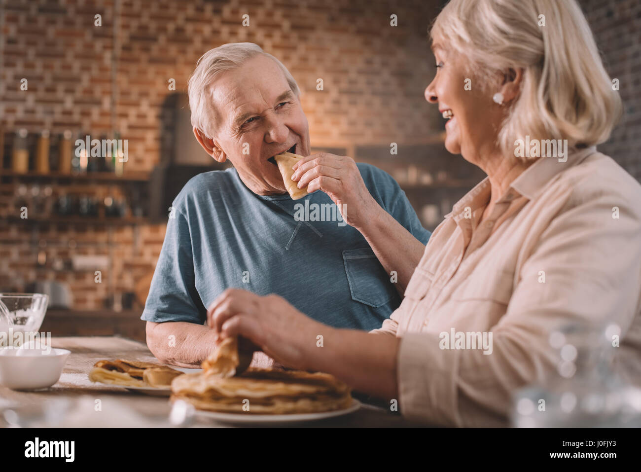 senior couple eating pancakes on kitchen at home Stock Photo