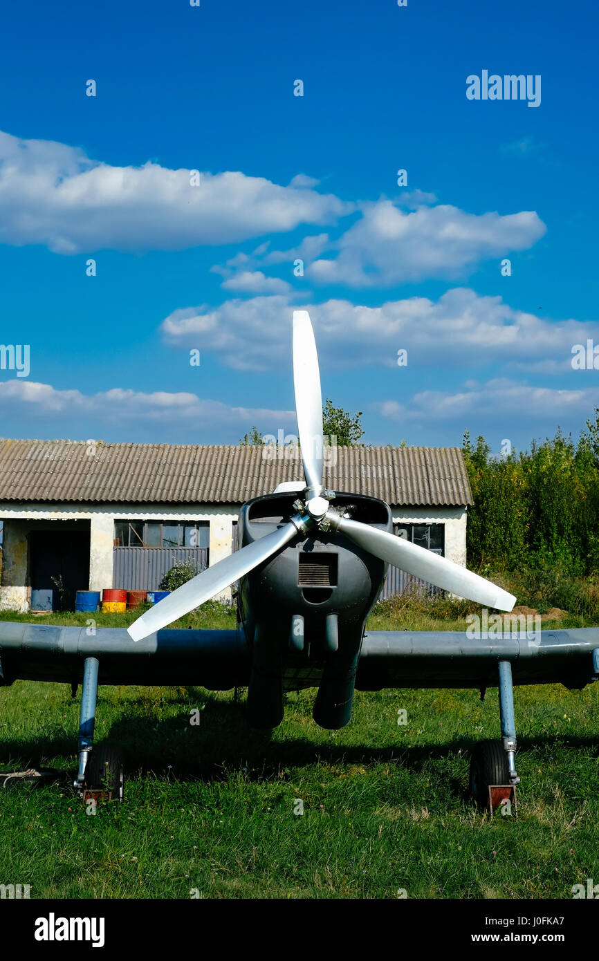Gray airpane parked on the grass at the airfield Stock Photo