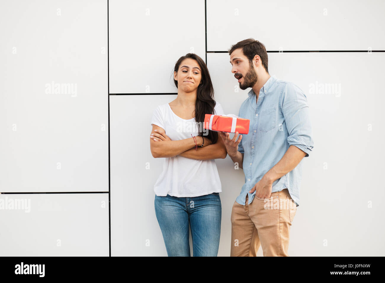 young man trying to reconcile his girlfriend offering her a gift Stock Photo