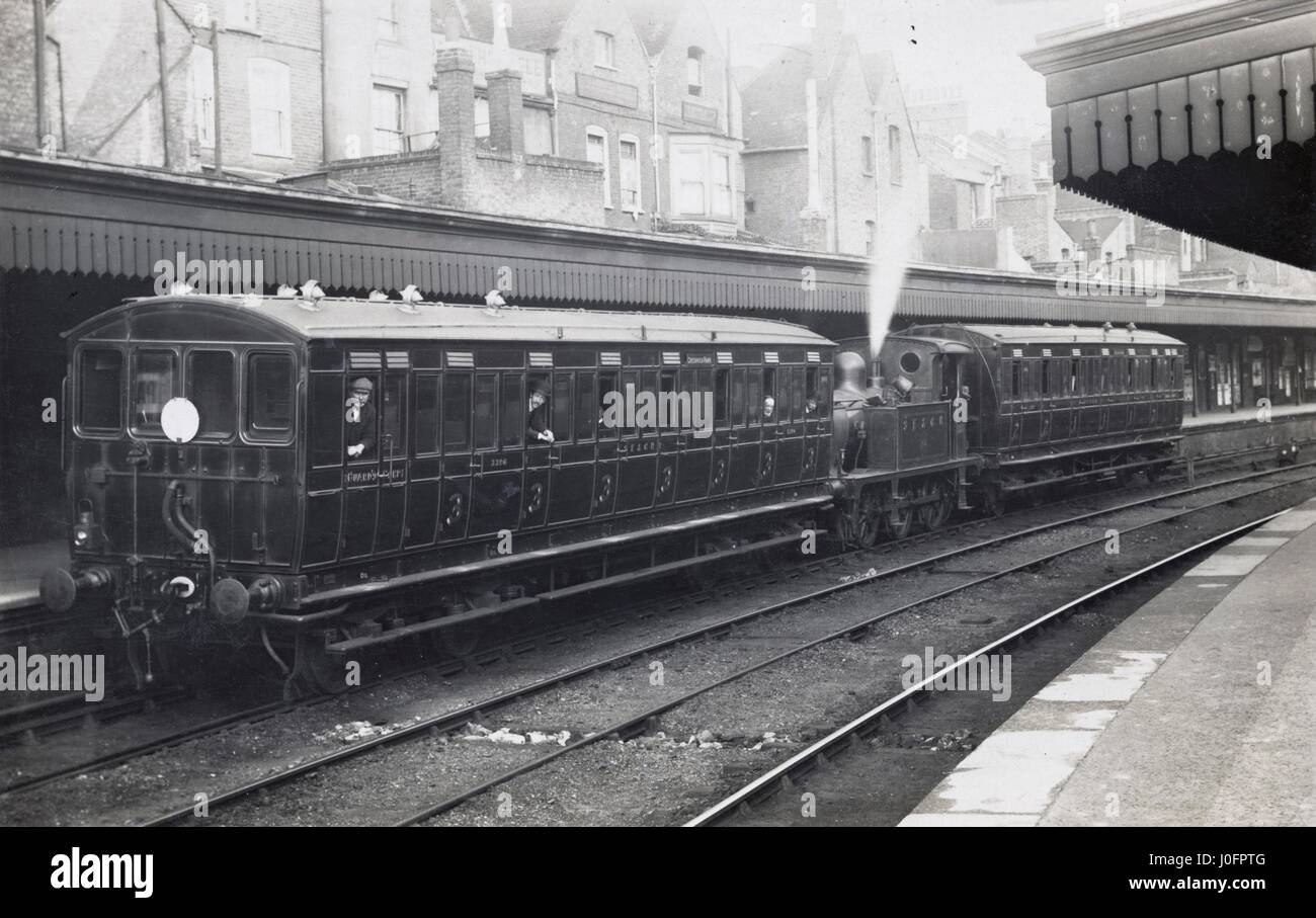 Railway station scene: two cars and engine, steam locomotive shunting carriages to platform Stock Photo