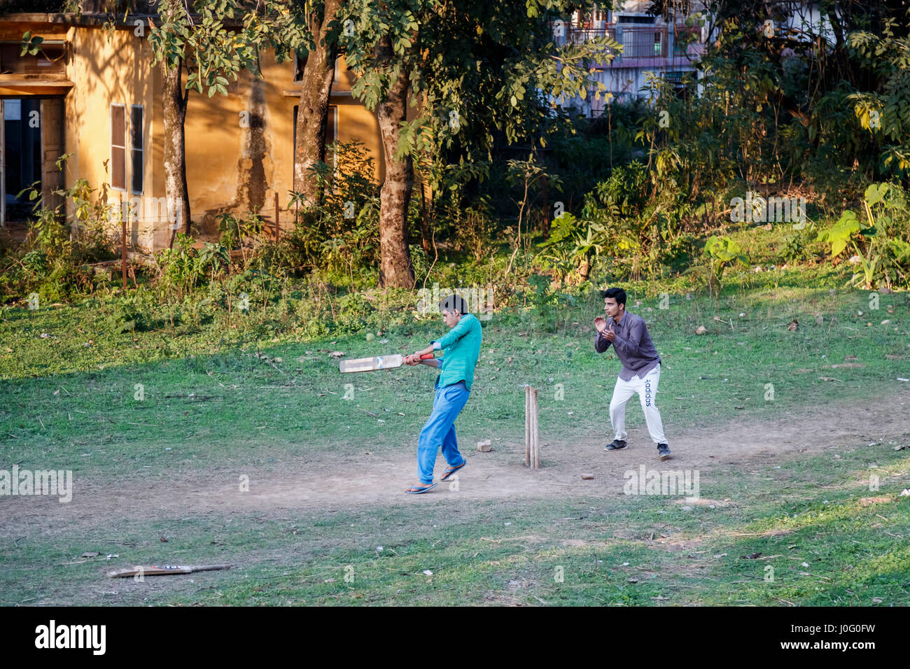 Two local Indian boys having fun playing a game of cricket on a dusty pitch in Pragpur, a heritage village in Kagra district, Himachal Pradesh, India Stock Photo