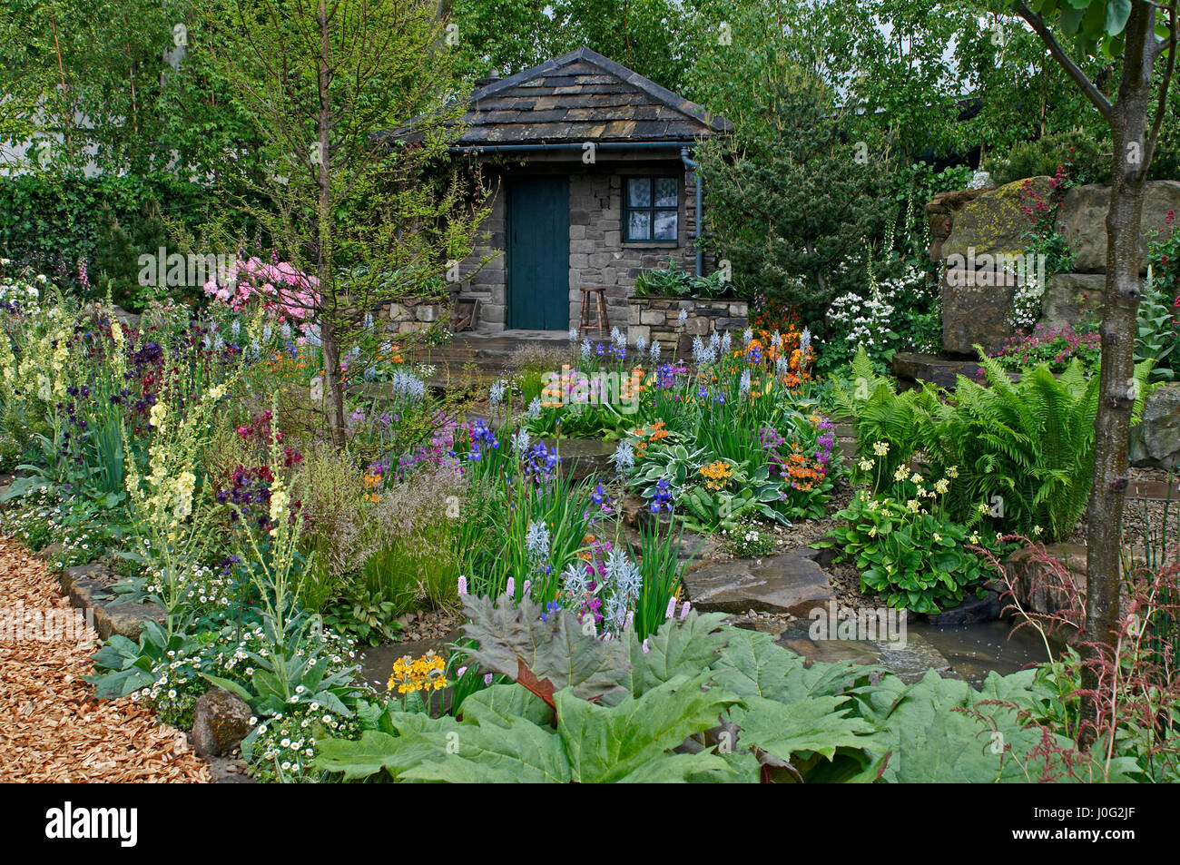 A country cottage and garden situated in a wooded rockery with a colourful display of flowers Stock Photo