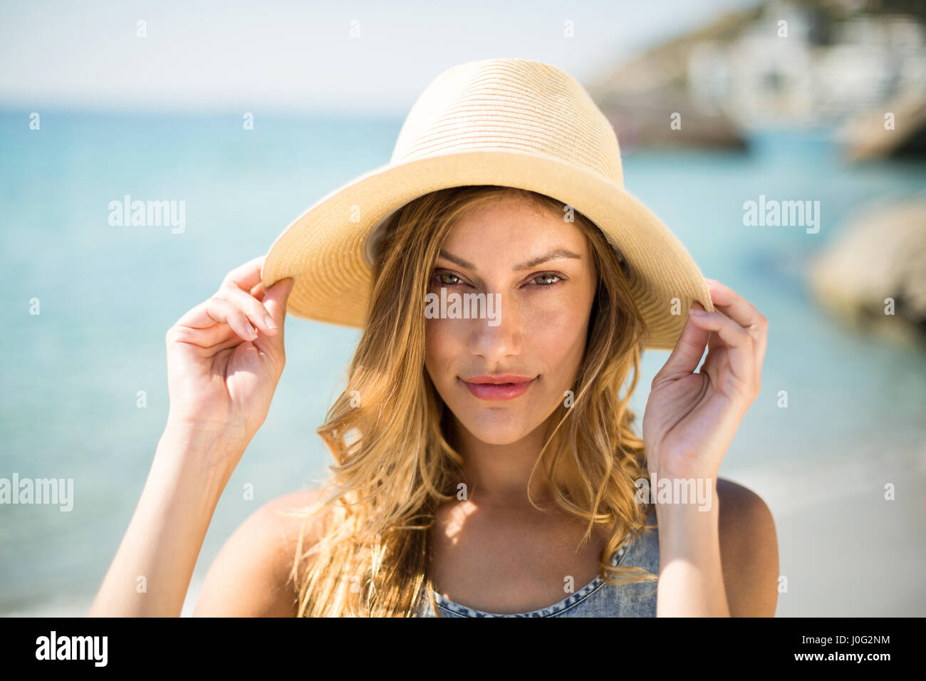 Close up portrait of beautiful young woman wearing sun hat on sunny day ...