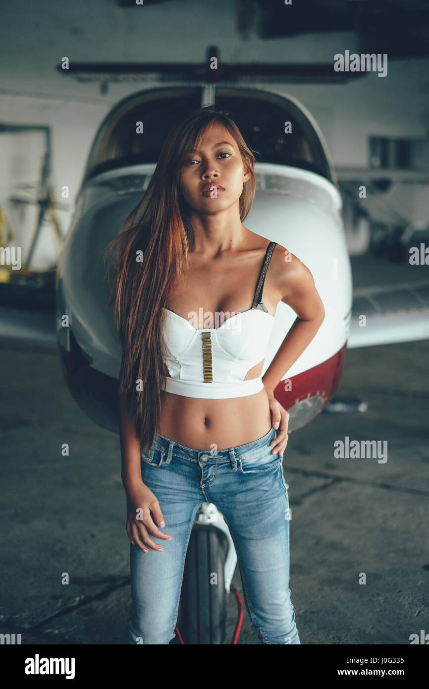 Beautiful female portrait in the airplane hangar, with modern aircraft Stock Photo