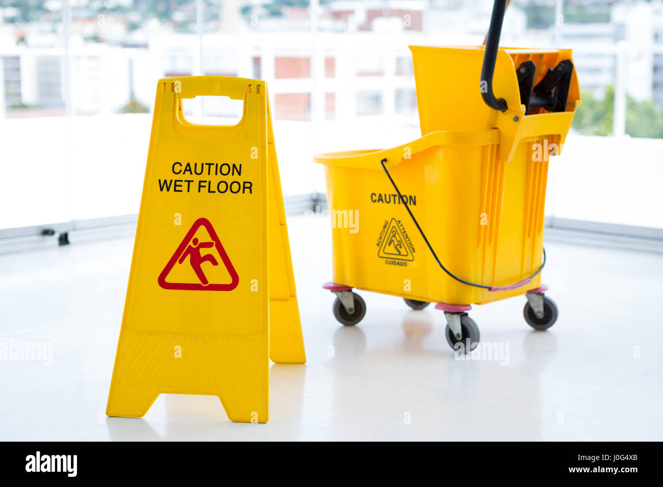 Sigh board with mop bucket in room against glass Stock Photo